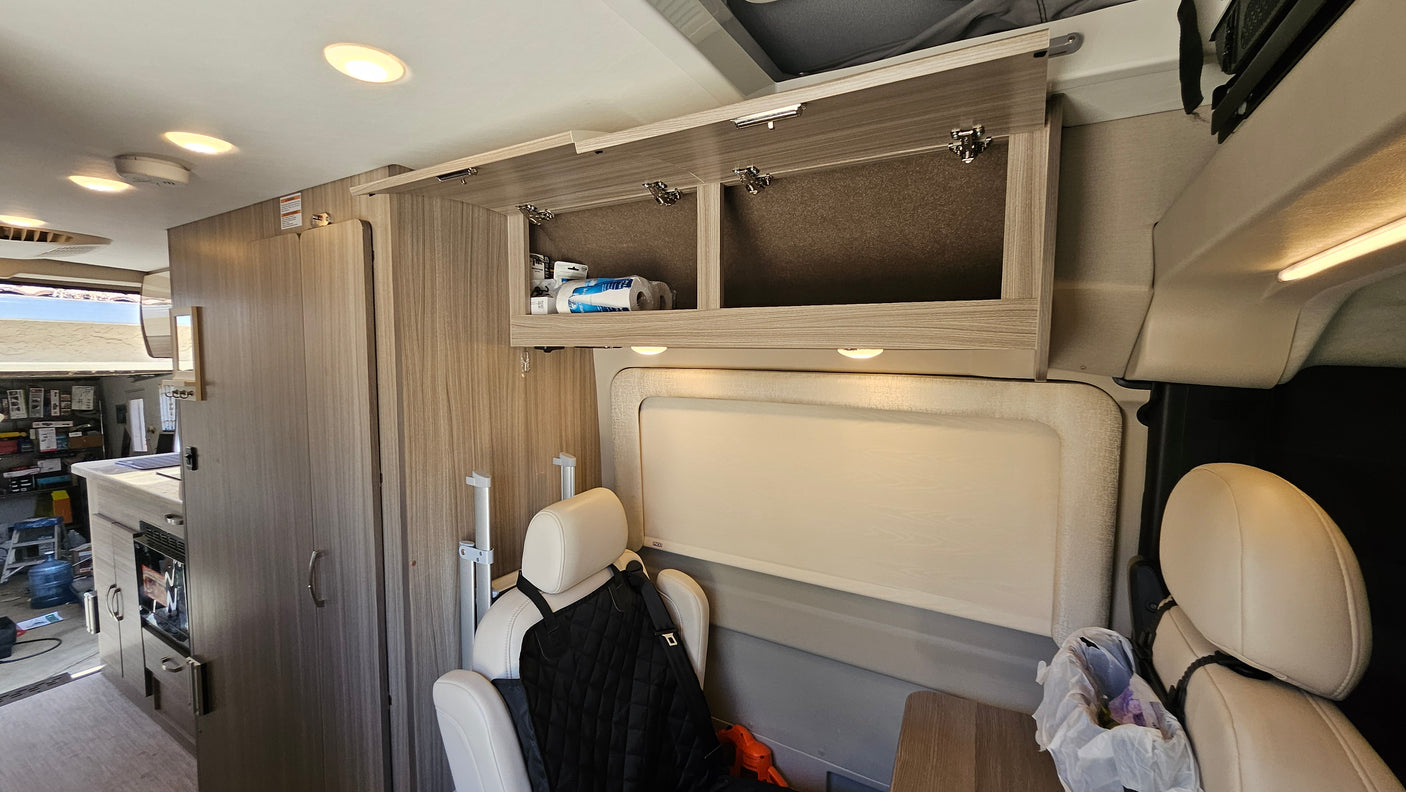 Inside a modern rv rental: light wood cabinets, comfortable seats, and a compact kitchen are visible in this camper van.