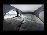 Cozy RV rental interior: quilted bed, large window with water view, plush toy, and lantern for comfy travel.