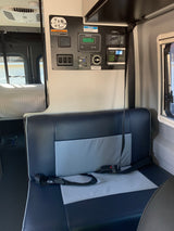 RV rental interior: A detailed view of the RV's control panel, showing power, water, and solar readouts, next to comfortable seating and a bed.