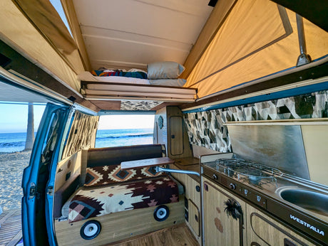 Experience beachside living in this classic Westfalia rv rental, featuring a pop-top bed, kitchen, and ocean views.