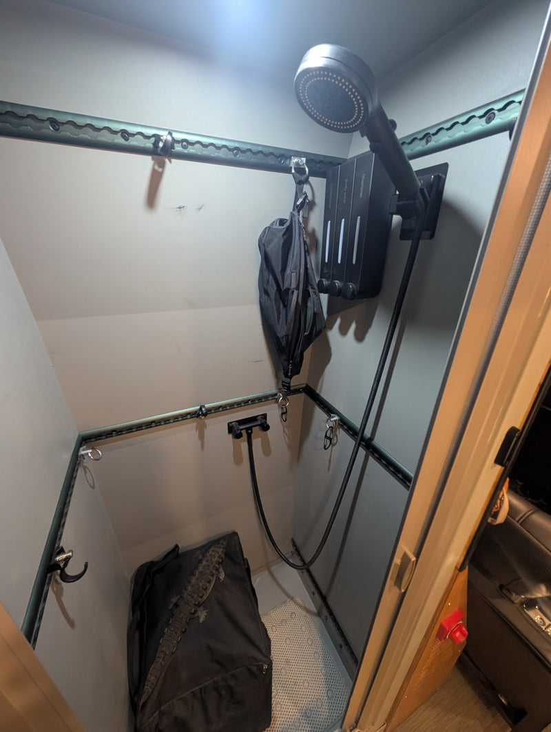 Compact rv rental shower features a handheld shower head, wall-mounted soap dispensers, and versatile E-track rails for storage. — photo 16