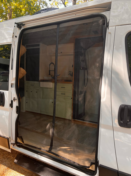 Inside an RV rental: a modern camper van conversion with a kitchen featuring green cabinets, sink, and a dedicated shower stall.