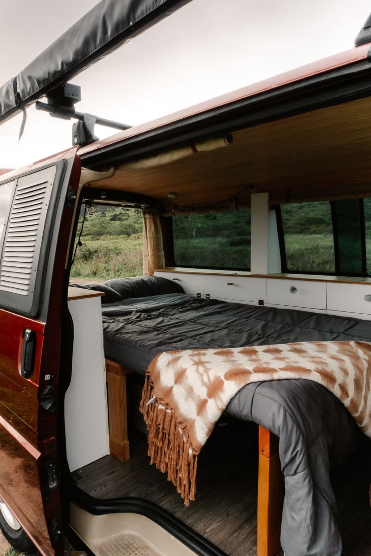  parked on sandy terrain near mountains.|Comfortable RV rental interior with a bed — photo 5