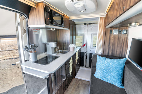 This RV rental features a modern interior with a compact kitchen, comfortable living area, and integrated shower space.