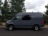This rugged dark gray Sprinter camper van, equipped with all-terrain tires, is an ideal RV rental for outdoor explorations.