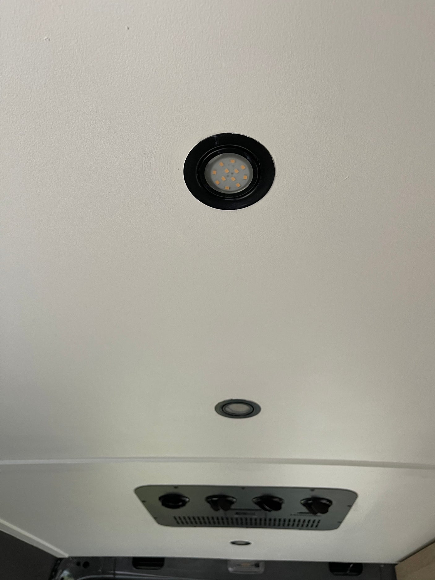 RV rental interior: White ceiling with bright LED recessed lights and a control panel featuring black knobs and vents.