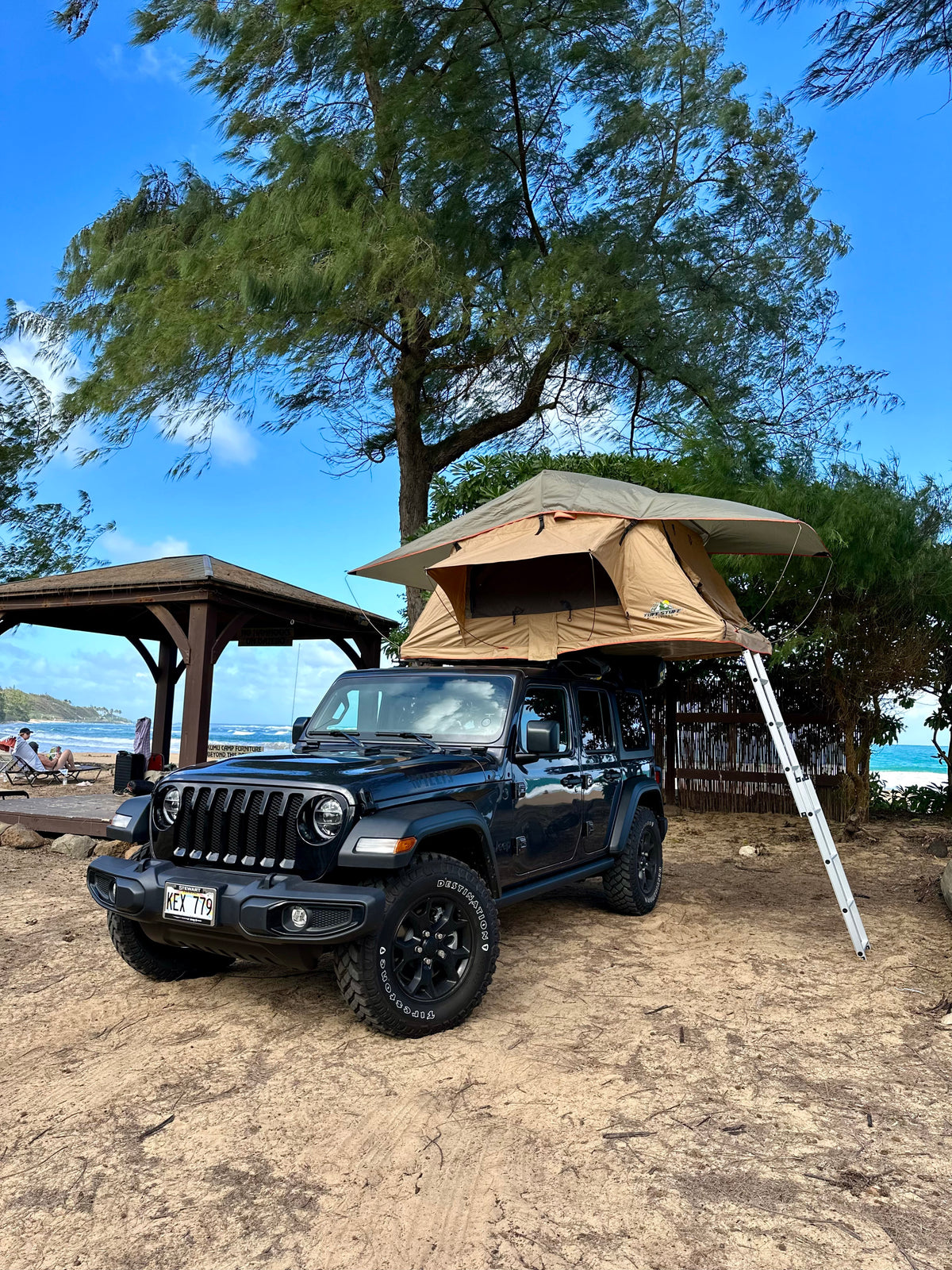 A black Jeep Wrangler, topped with a tent, parked by the beach. This RV rental offers unique oceanfront camping. — photo 9