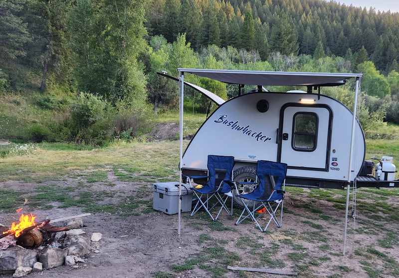 Camping with an RV rental: a Bushwhacker camper, chairs, and a cozy campfire surrounded by nature. — photo 14