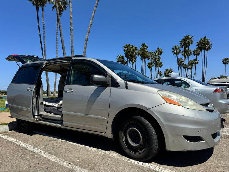 A silver camper minivan with open doors and trunk, revealing its interior bed setup. Ideal rv rental for a sunny adventure. — photo 3