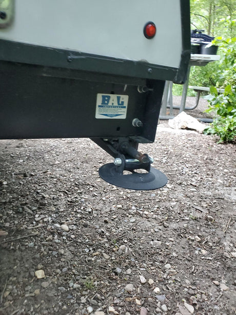 An RV rental's stabilizer leg with a BAL brand label, resting on gravel. Essential for a steady camp setup.