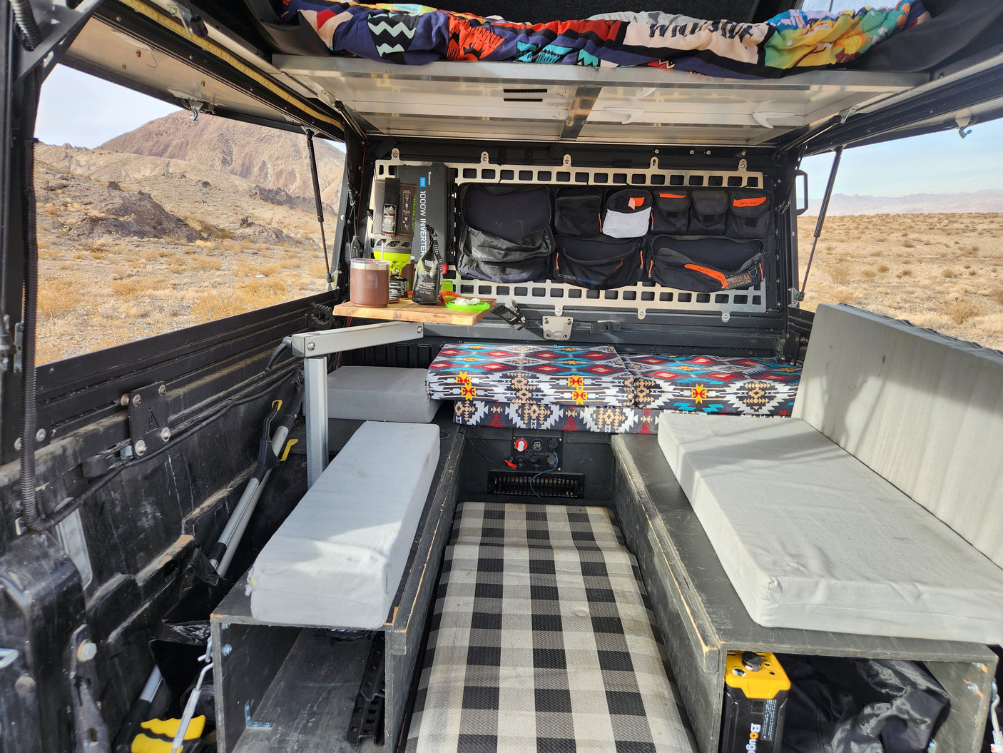 Custom truck camper interior with organized storage & cozy bed. Explore the desert – a versatile RV rental option.
