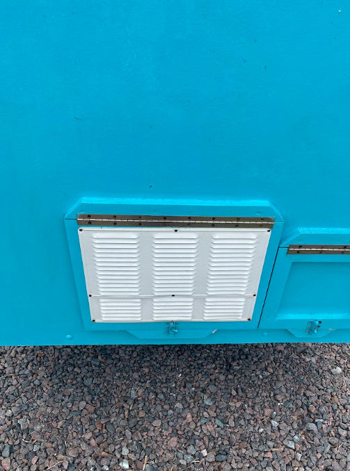 Bright blue RV exterior with a white louvered access panel for systems like refrigeration, common on an RV rental.