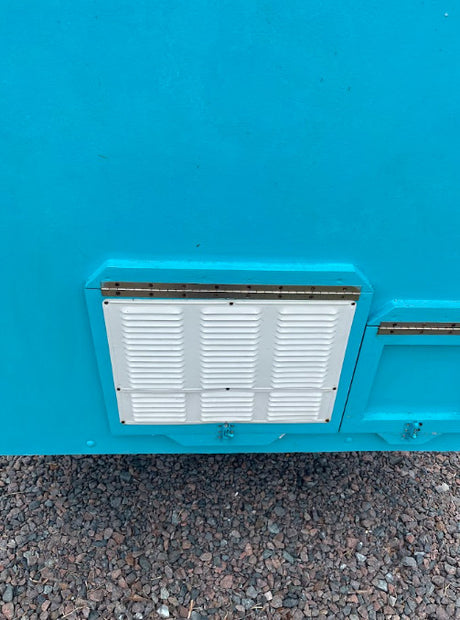 Bright blue RV exterior with a white louvered access panel for systems like refrigeration, common on an RV rental.