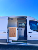 This RV rental offers a custom camper van interior with a modern kitchen, sink, and separate restroom, ready for road trips.