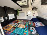 This rv rental offers a comfy bed with a fun camping blanket, AC, and fan. Perfect for your next adventure!