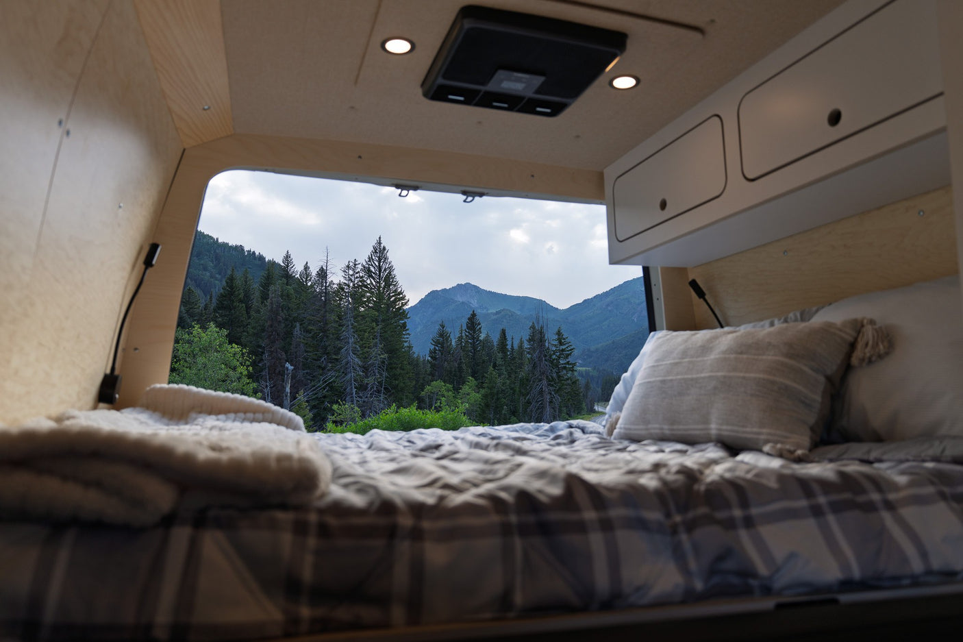Cozy RV rental interior with a comfortable bed & stunning mountain view. Perfect for outdoor adventures.