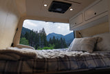 Cozy RV rental interior with a comfortable bed & stunning mountain view. Perfect for outdoor adventures.
