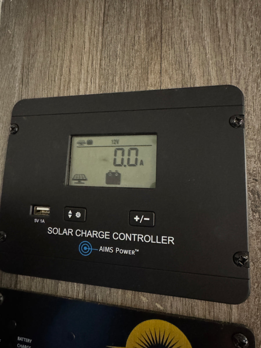An AIMS Power solar charge controller in an rv rental. It displays 12V, 0.0A, and has a 5V 1A USB port visible.