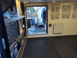 Spacious RV rental interior with organized storage, fold-down table, and black textured floor, looking out rear door.