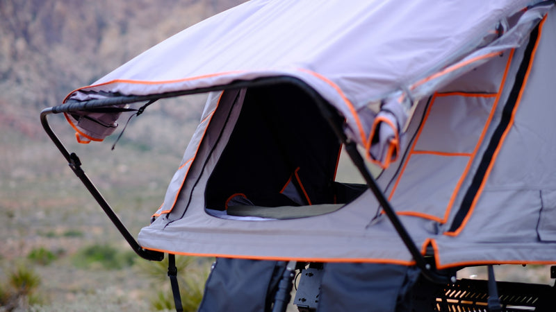 Explore with an RV rental alternative: a grey rooftop tent with orange trim, open & ready for camping in the desert. — photo 18