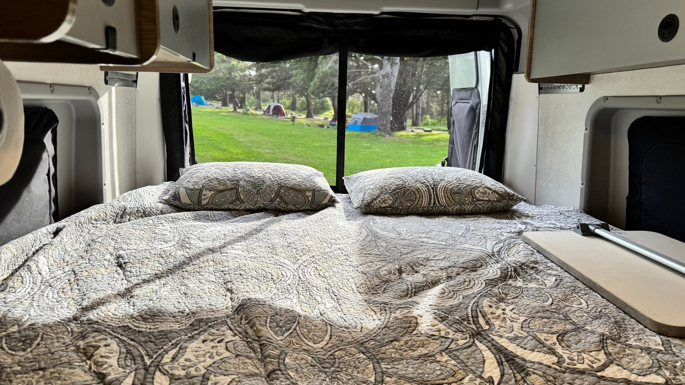  surrounded by other campers.|Explore this RV rental! Open rear van doors reveal a cozy bed — photo 8