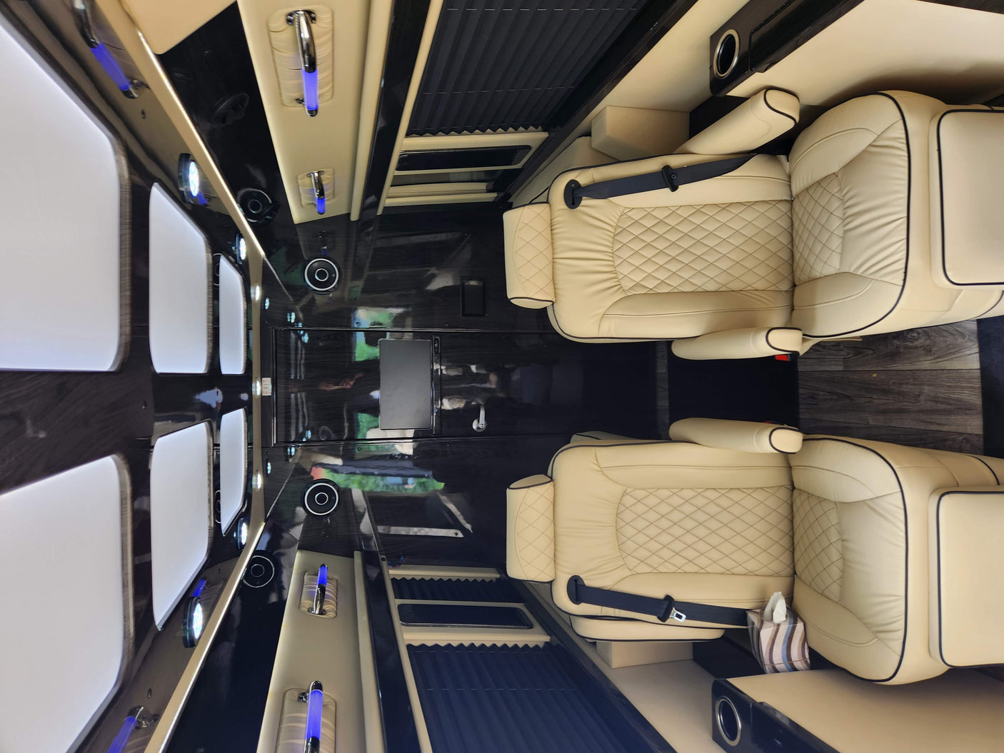 Step inside this premium RV rental: a spacious custom van interior with luxurious leather seating, ambient lights, and modern amenities.