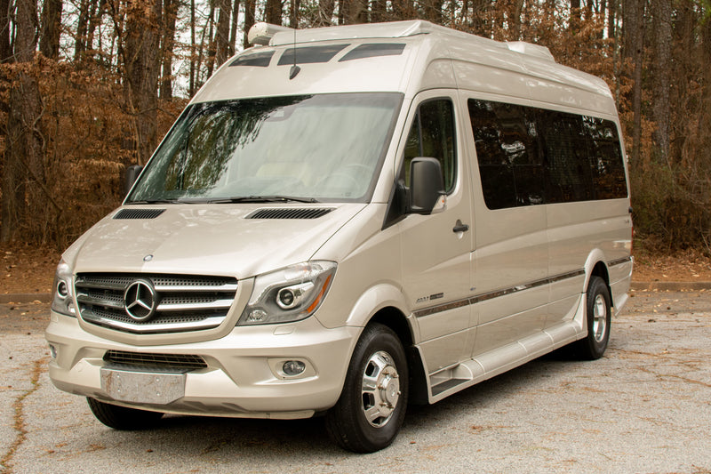 This champagne Mercedes-Benz Sprinter RV, ideal for an RV rental, is parked outdoors amidst trees. — photo 2