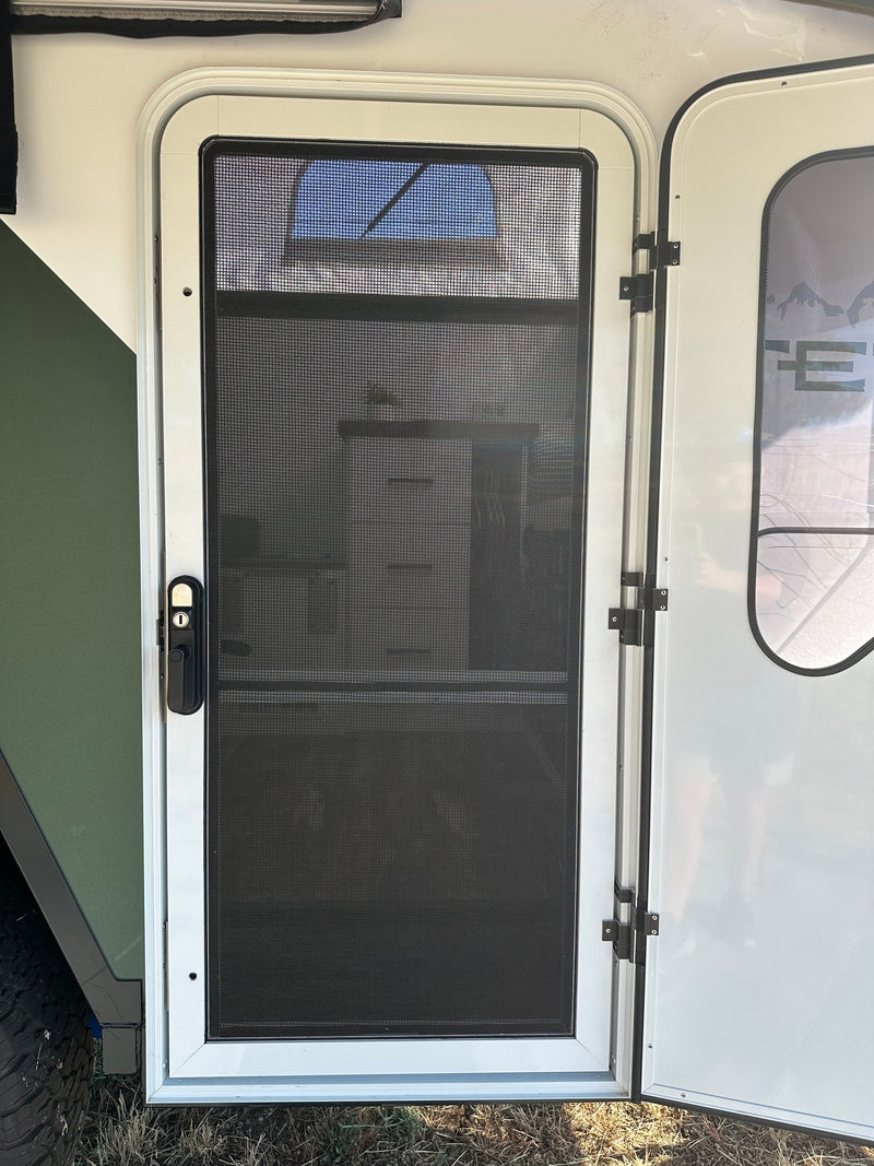 A white screen door with black mesh and handle on an RV rental, offering fresh air for your camping adventure. — photo 17