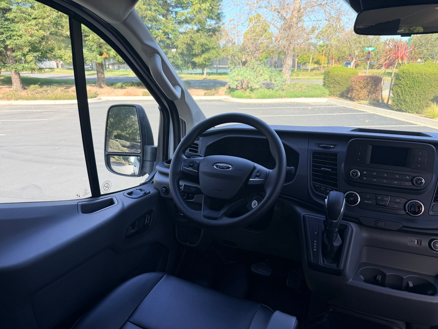 Inside a Ford van RV rental, showing the driver's seat, steering wheel, and dashboard controls for your next road trip.