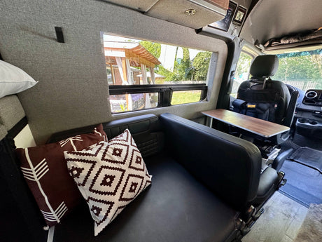 RV rental interior: comfy lounge seating, a functional table, and scenic window views from this modern camper van.