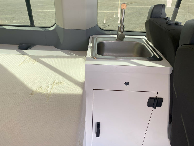 RV rental interior showing a compact sink, faucet, under-sink storage, and a mattress with bamboo patterns. — photo 2