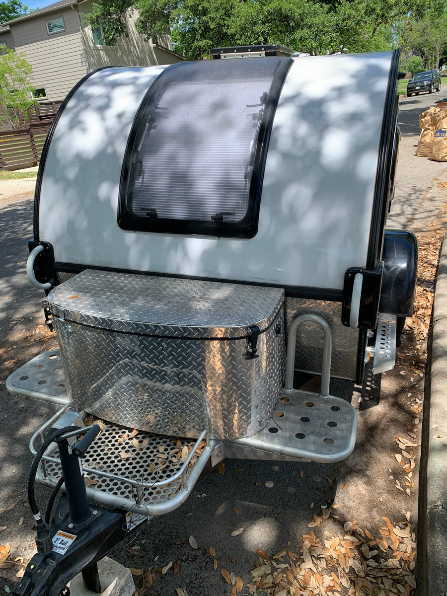 This white compact teardrop RV, available for RV rental, features a front diamond-plate storage box and large window.