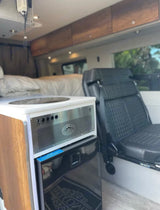 Cozy rv rental interior: kitchenette with fridge, comfy bed, and passenger seating. Perfect for road trips!