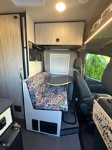 This RV rental's inviting interior features a vibrant dinette, round table, and storage, ready for adventures.
