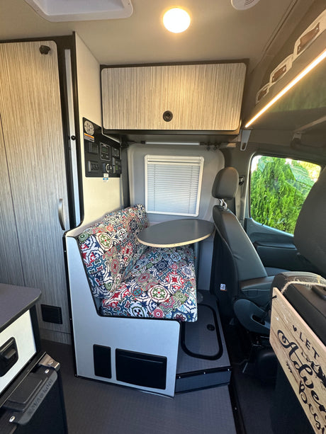 This RV rental's inviting interior features a vibrant dinette, round table, and storage, ready for adventures.