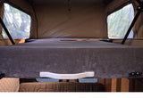 Elevated bed in this RV rental pop-top camper, with clear windows offering outdoor views.