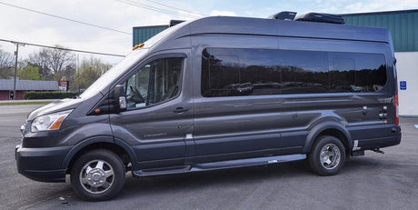 A dark gray, high-top RV rental, converted from a van, is parked. Ideal for travel or camping.