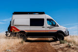 Storyteller Overland MODE 4x4 camper van, perfect for rv rental adventures, on a dirt path under a clear blue sky.