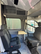 RV rental van interior with versatile seating, a collapsible table, and wall storage for comfy road trips.