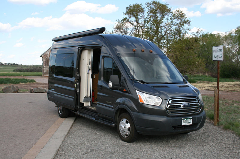 Dark grey Ford Transit van, an RV rental, with open side door showing its interior, parked by an 'Oversized Vehicles' sign. — photo 6