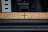 RV rental interior: a custom wood panel with 'ADVENTURE AWAITS' and compass art. Ready for your next travel journey.