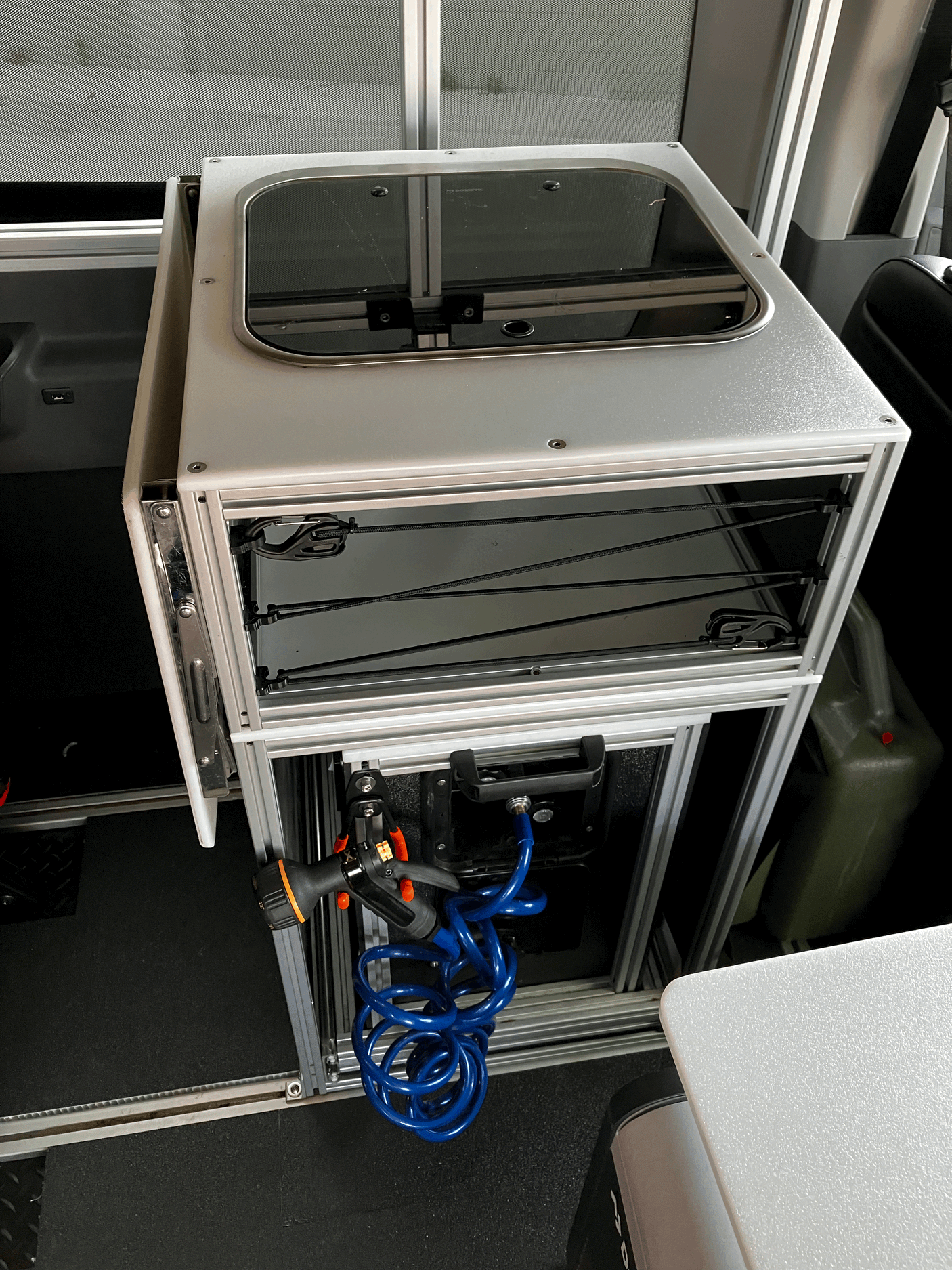Inside an RV rental: a compact modular kitchen with glass-top sink, storage, and a convenient pull-out hose shower.