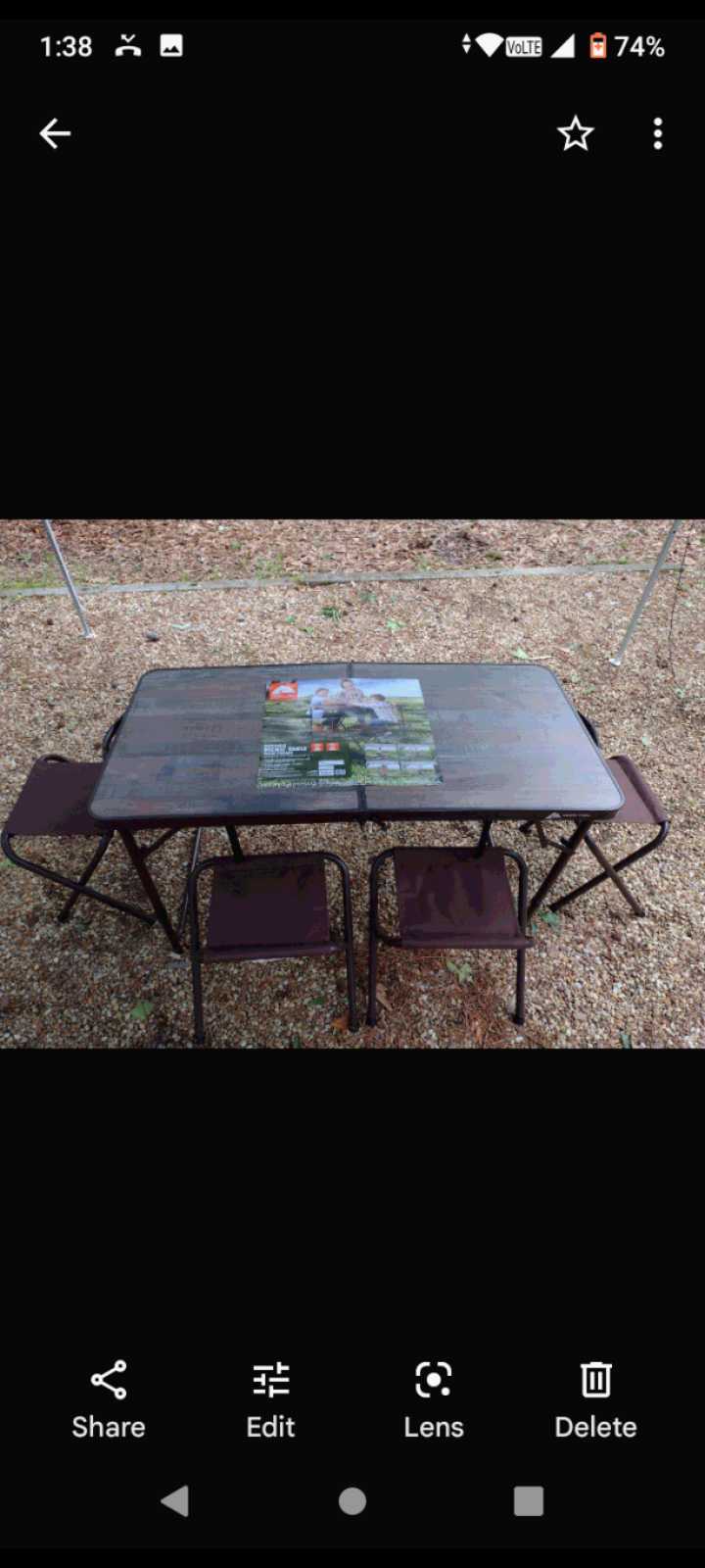 Portable outdoor table & 4 folding chairs on gravel, ideal for an RV rental trip or camping. Product info on table.