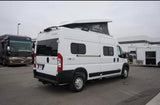 A white Winnebago Solis camper van with an extended pop-top roof, available for RV rental, parked among other recreational vehicles.