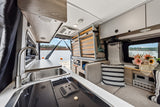 Inside a modern RV rental: functional kitchen, flexible sleeping area, and serene lake view from the rear.