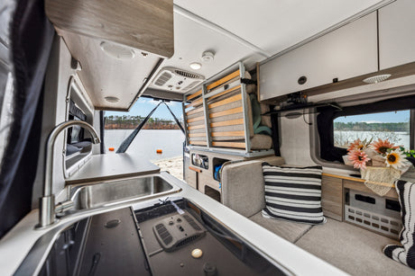Inside a modern RV rental: functional kitchen, flexible sleeping area, and serene lake view from the rear.