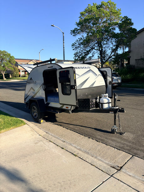 This compact FreeSolo teardrop travel trailer RV rental is parked on a residential street, doors open, ready for its next adventure.