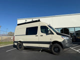 Beige Mercedes Sprinter van, equipped for van life adventures, perfect as an rv rental, parked outdoors on a sunny day.
