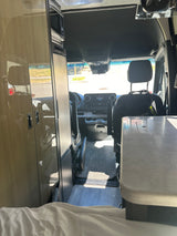 Inside this Mercedes-Benz RV rental: a bright interior with kitchenette, cockpit, and road view.