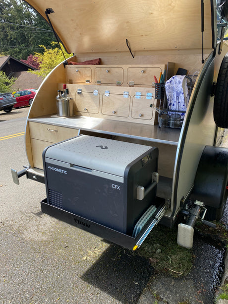 Teardrop trailer RV rental's outdoor galley with Dometic cooler on pull-out, counter, & storage. Perfect for camping adventures.